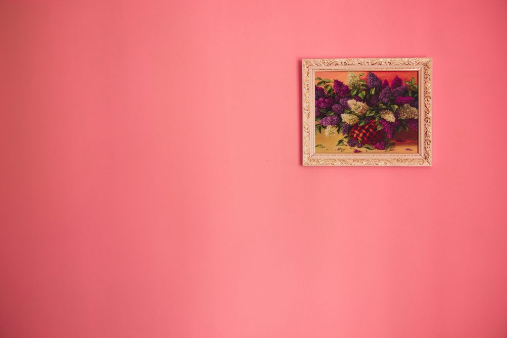 Beautiful pink wall and a photo of fruit. Like Grapes and stuff or maybe flowers.